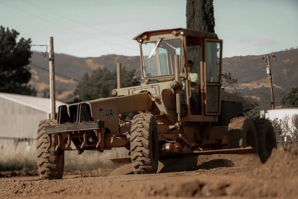 A Cupples Excavating motor grader working a dirt site with golden Mendocino hills behind